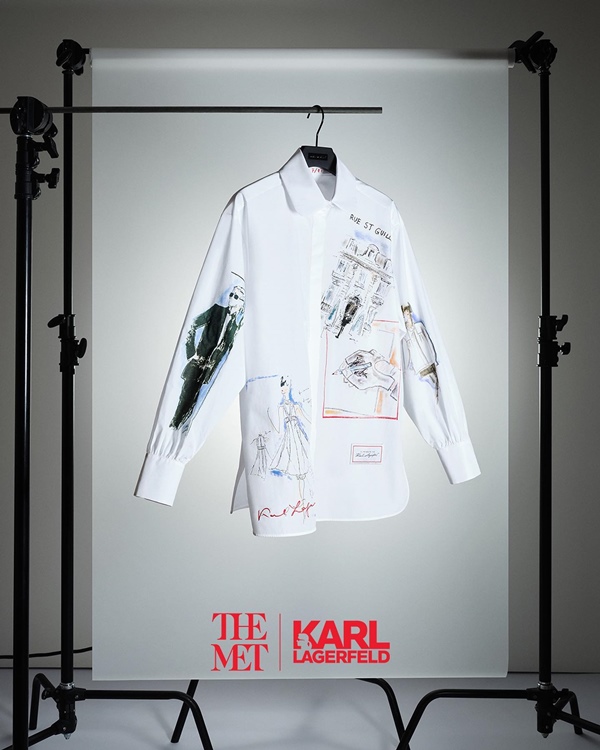 Foto de um estúdio com tripés e uma araca com cabide pendurado, em que é possível ver uma camisa branca de botão. A peça é estampada com ilustrações do estilista alemão Karl Lagerfeld