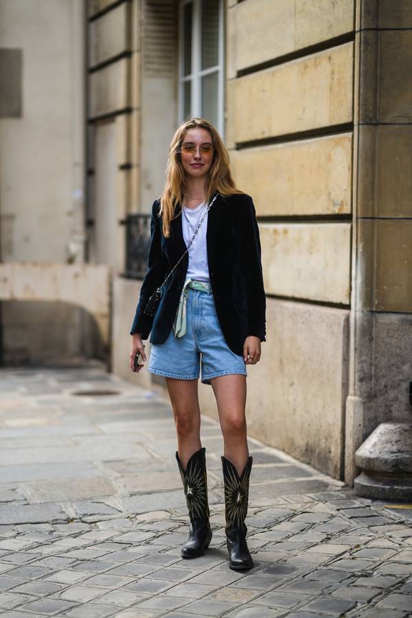 Look com bota western, short jeans, camiseta branca e blazer preto