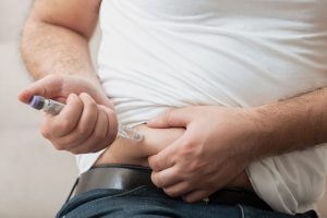 imagem colorida de homem aplicando caneta injetável de insulina na barriga