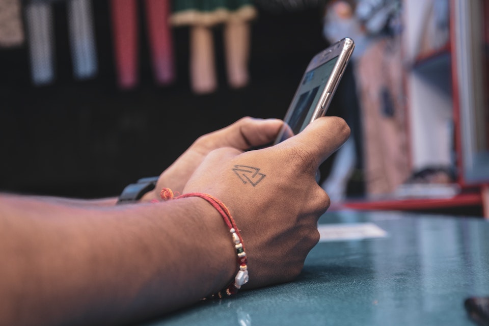 Mãos com tatuagem segurando celular - Metrópoles