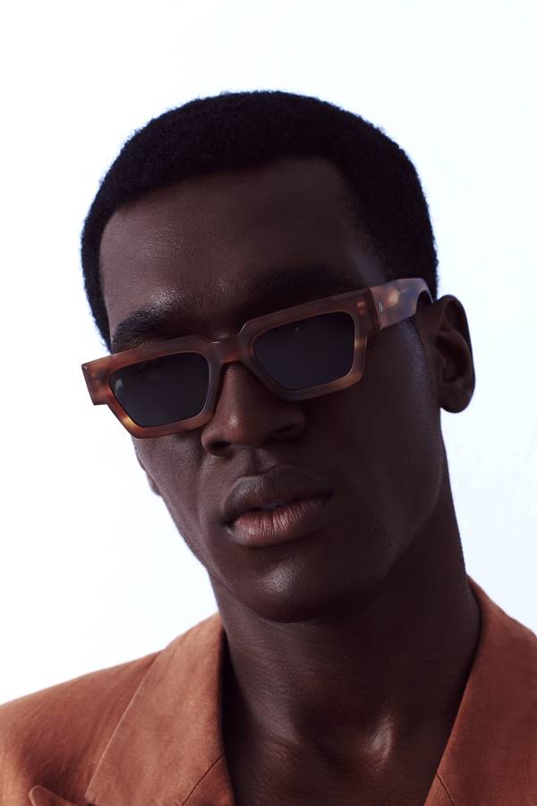 Modelo negro com cabelo com corte baixo usa óculos com lentes escuras - Metrópoles