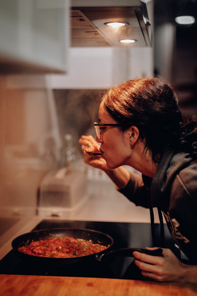 Mulher experimentando comida enquanto cozinha - Metrópoles