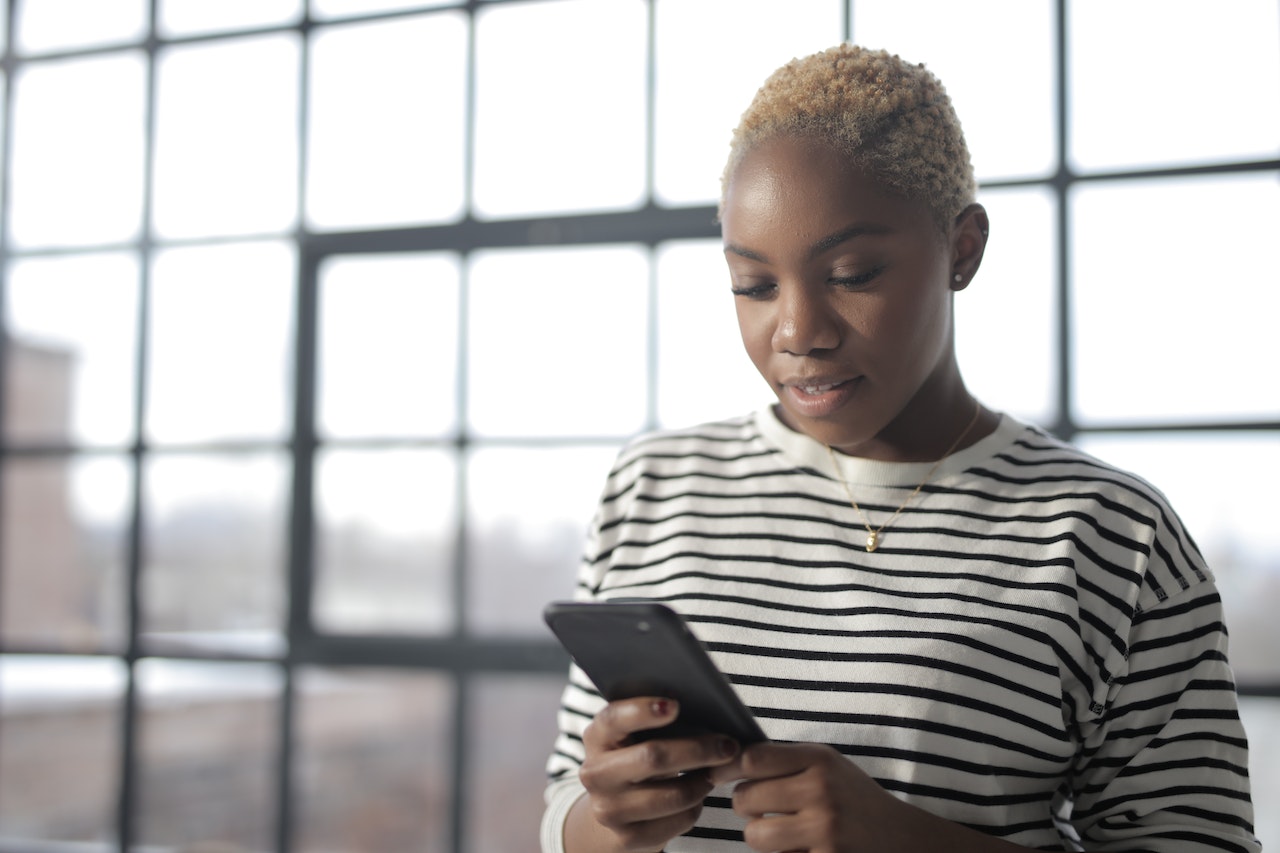 Mulher preta segurando celular - Metrópoles