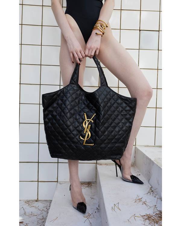 Modelo segura bolsa Icare da marca Saint Laurent. A bolsa é grande, na cor preta e tem logo da marca YSL - Metrópoles 