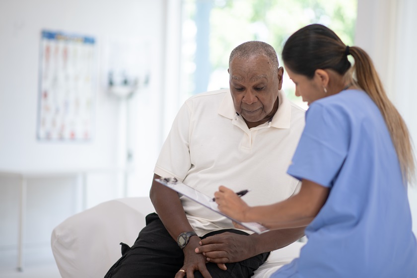 Homem negro de camisa branco sentado na maca observa as recomendações da médica - Metrópoles