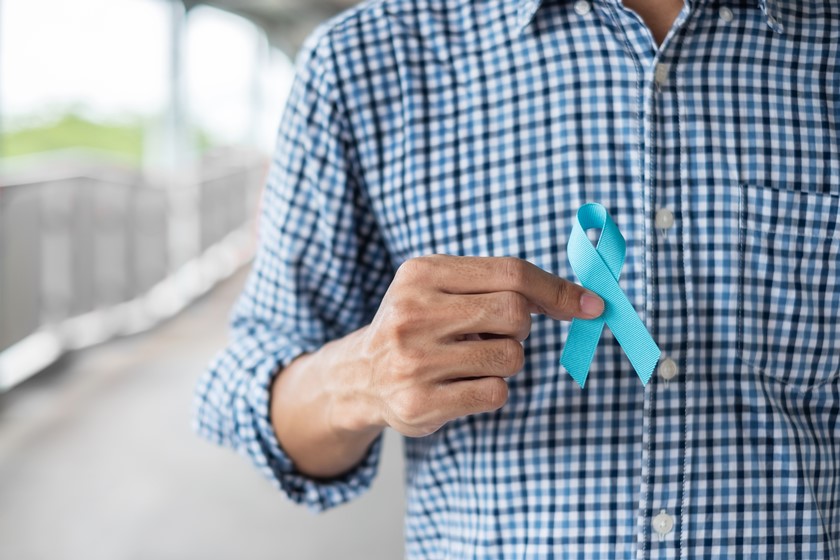 Hoem de camisa azul segurando o laço do Novembro Azul - Getty Images