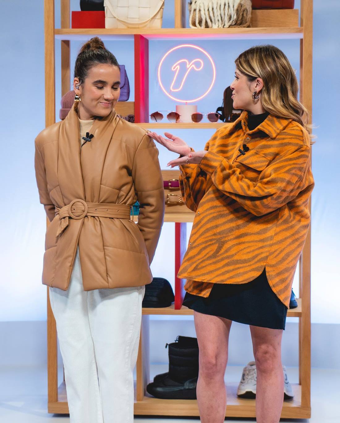 Duas mulheres brancas e jovens durante a gravação de um comercial para a Renner. A primeira possui o cabelo castanho e liso, amarrado em um coque, e usa um casaco caramelo e uma calça branca. A segunda tem o cabelo loiro e ondulado e usa um short preto e uma camisa amarela. - Metrópoles