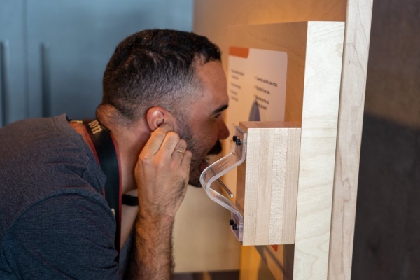 Homem branco de cabelo curto câmera no pescoço interagindo com exposição interativa no Sesi Lab