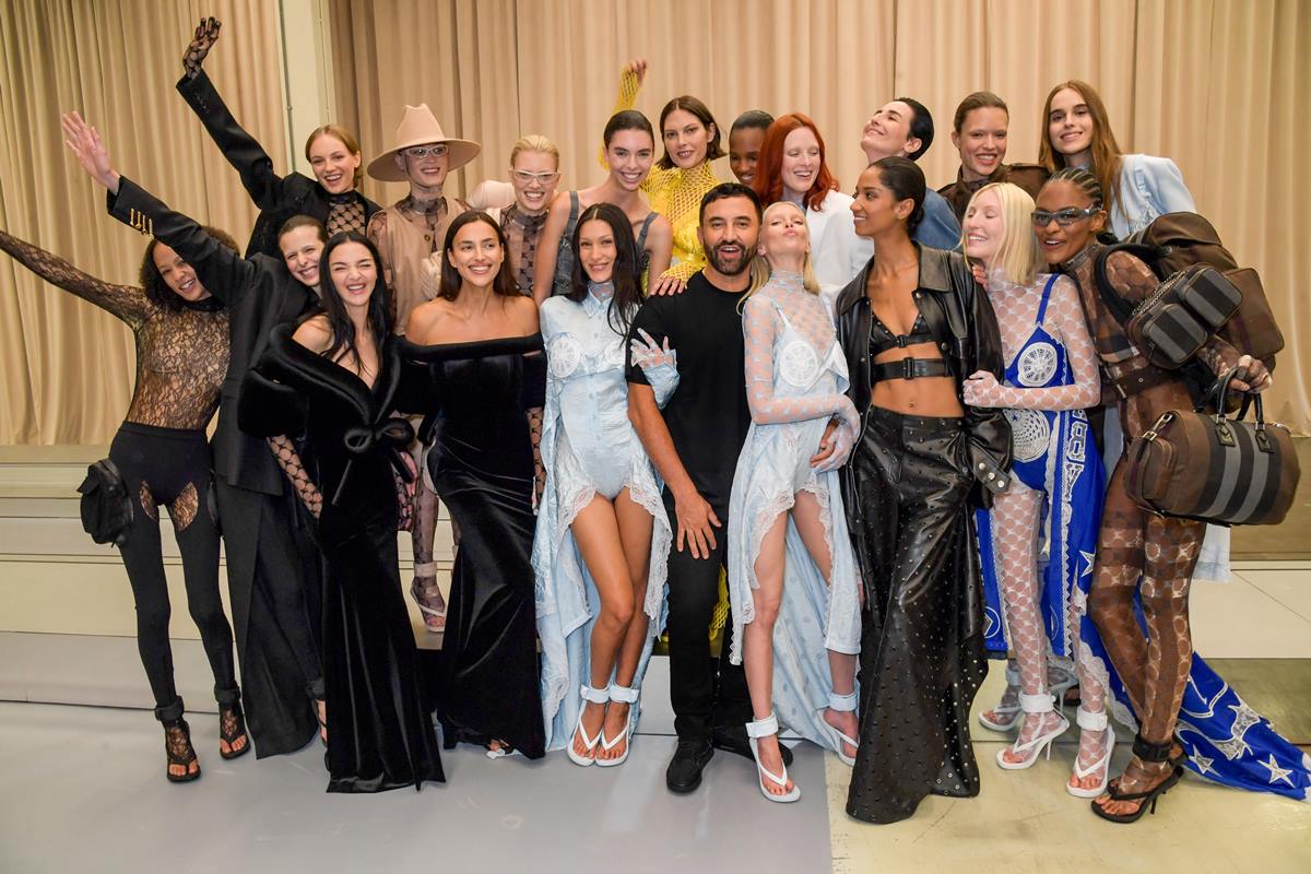 O estilista da Burberry, Riccardo Tisci, posa nos bastidores do desfile da marca com modelos como Fran Summers, Mariacarla Boscono, Irina Shayk, Candice Shepstone, Bella Hadid, Stella Maxwell, Erin O'Connor e Ella Richards. O evento foi na Semana de Moda de Londres em setembro de 2022. - Metrópoles