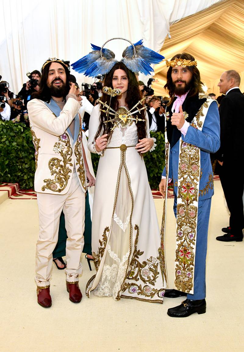 O estilista Alessandro Michele e os cantores Lana Del Rey e Jared Leto participam do Met Gala 2018 em Nova York. Eles usam roupas da marca Gucci que fazem referência aos trajes usados por papas e membros da Igreja Católica. - Metrópoles