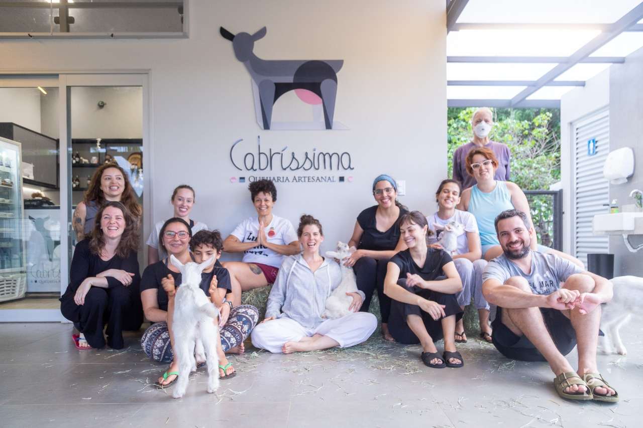 Na foto, várias epssoas reunidas e sentadas no chão com pequenas cabras - Metrópoles