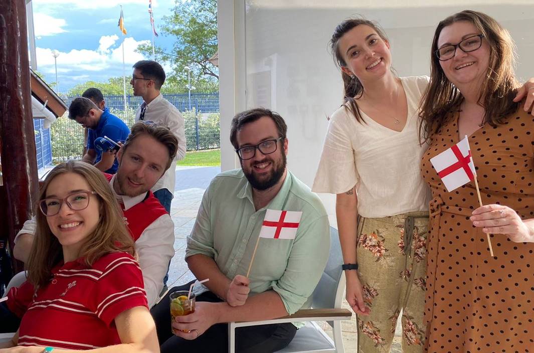 Dois homens e três mulheres posando para a foto e sorrido enquanto seguram bandeiras do País de Gales e da Inglaterra