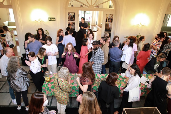 Na imagem com cor, grupo de pessoas reunidas em salão - Metrópoles