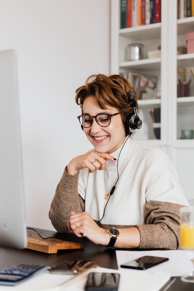 Mulher jovem sorrindo de frente para o computador - Metrópoles