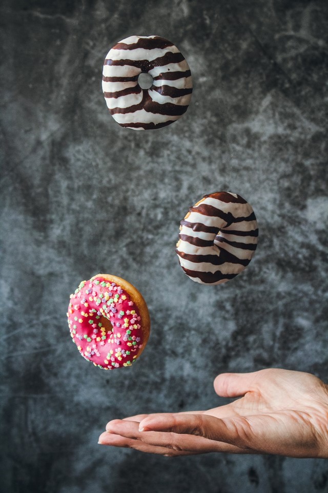 Mão jogando três donuts para cima - Metrópoles