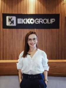 Na foto está Ingrid Holanda sorrindo e há um fundo da EkkoGroup atrás - Metrópoles