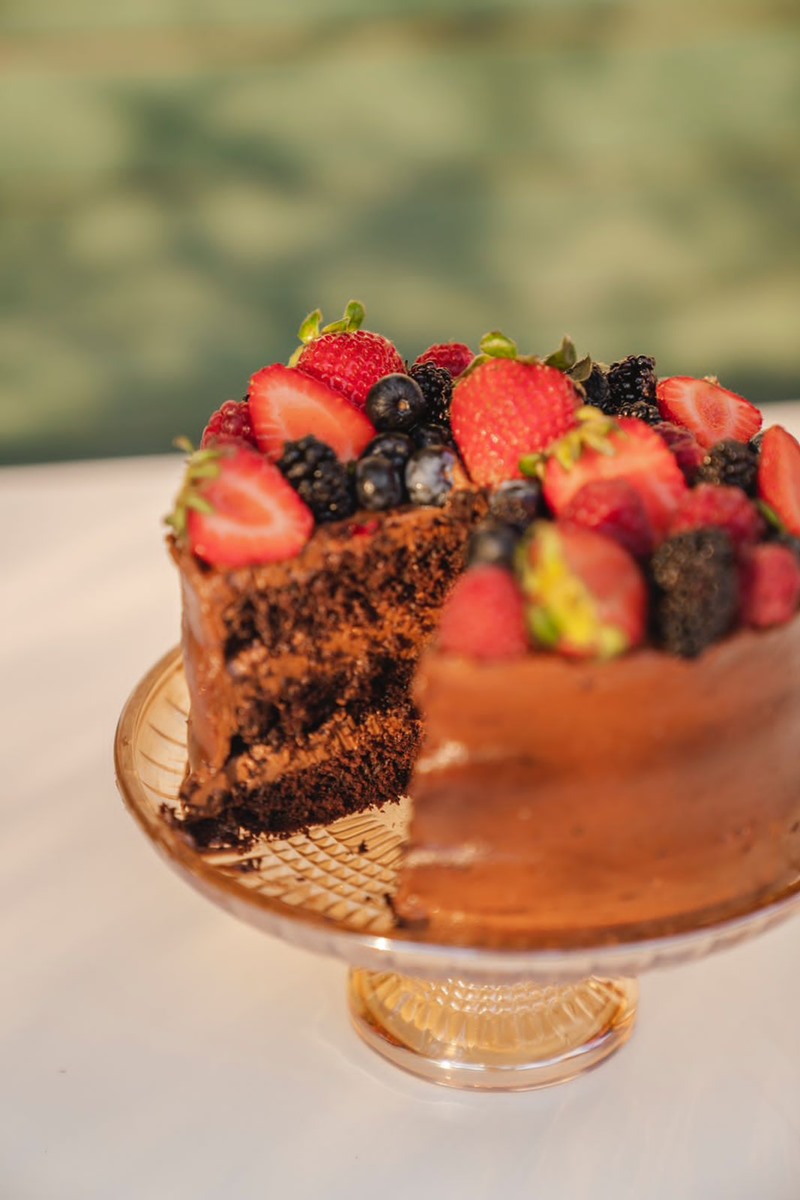 Foto colorida de bolo de chocolate recheado e com frutas vermelhas no topo - Metrópoles