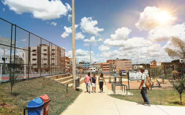 Fotografia colorida mostrando pessoas caminhando ao lado de uma quadra de futebol-Metrópoles