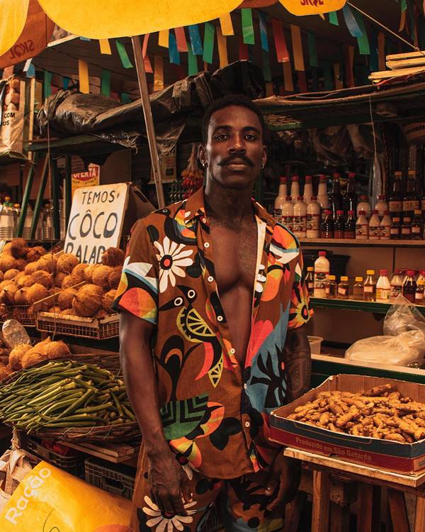 Modelo negro usa camisa de collab da Dane-se a frente de uma barraca de frutas - Metrópoles 