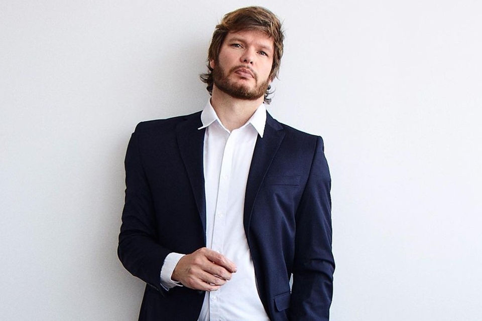 Foto colorida de homem branco de barba com blazer azul-escuro e blusa branca - Metrópoles