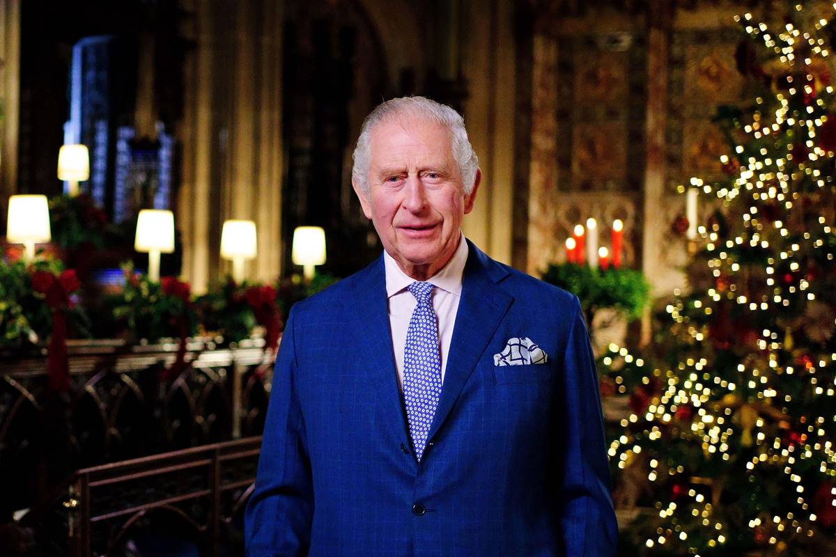 Foto colorida de homem idoso branco com terno azul. Ao fundo, estão velas e uma árvore de Natal - Metrópoles