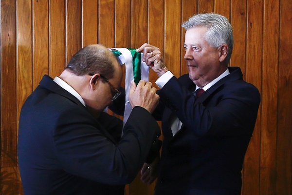 Fotografia colorida de homem colocando faixa em outro homem