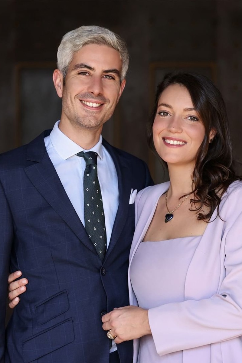 Foto colorida de homem branco e de terno ao lado de mulher branca, com cabelos castanhos e roupas no tom lavanda - Metrópoles