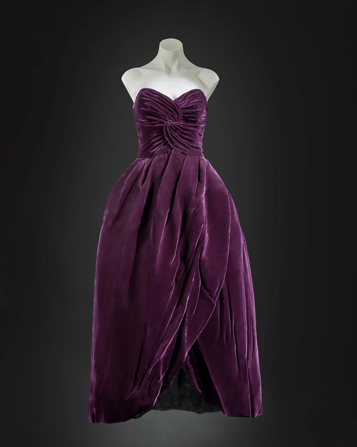 Vestido roxo de veludo, sem alça e com um bustiê franzido, da coleção de outono de 1989 do estilista Victor Edelstein. A peça, feita em tecido camurça, foi usada pela princesa Diana. - Metrópoles