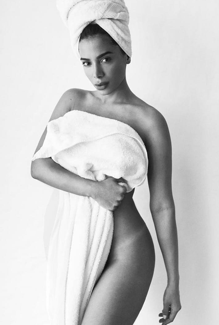 A cantora Anitta, uma mulher morena e jovem, de cabelo liso castanho, posa em um fundo branco seminua. A foto faz parte do projeto Towel Series, do fotógrafo Mario Testino. Nessa série, os personagens aparecem tampando parte do corpo apenas com toalhas brancas. - Metrópoles