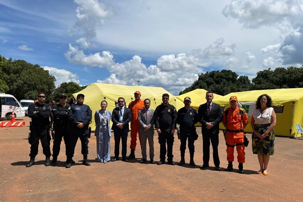 Fotografia de grupo de pessoas em pé com lonas amarelas ao fundo