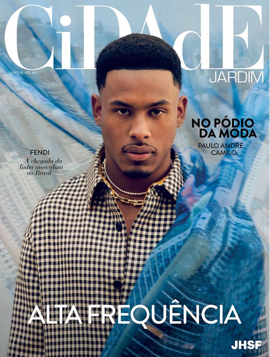 O ex-BBB e atleta Paulo André, um homem jovem e negro, de cabelo cacheado curto, posa para foto na capa da revista Cidade Jardim. Ele usa uma camisa quadriculada preta e branca e correntes de ouro. - Metrópoles