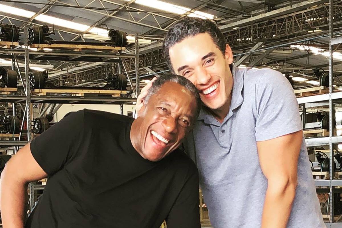 Foto colorida de homem negro e sorridente ao lado de homem pardo e sorridente - Metrópoles