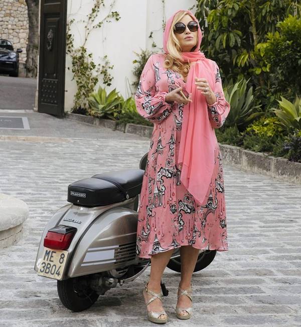 Tanya McQuoid, da série White Lotus. Na imagem, ela usa vestido florido e lenço rosa na cabeça - Metrópoles