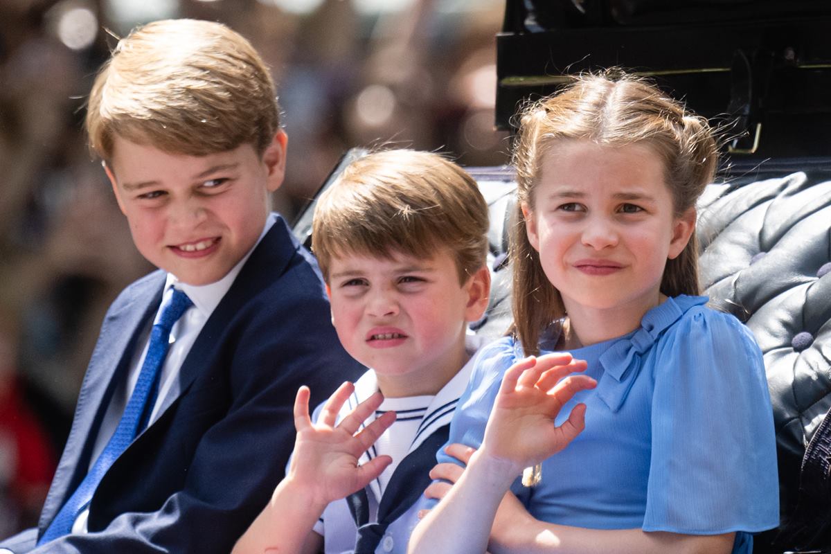 Foto colorida de três crianças branca e loiras acenando e com cara triste - Metrópoles