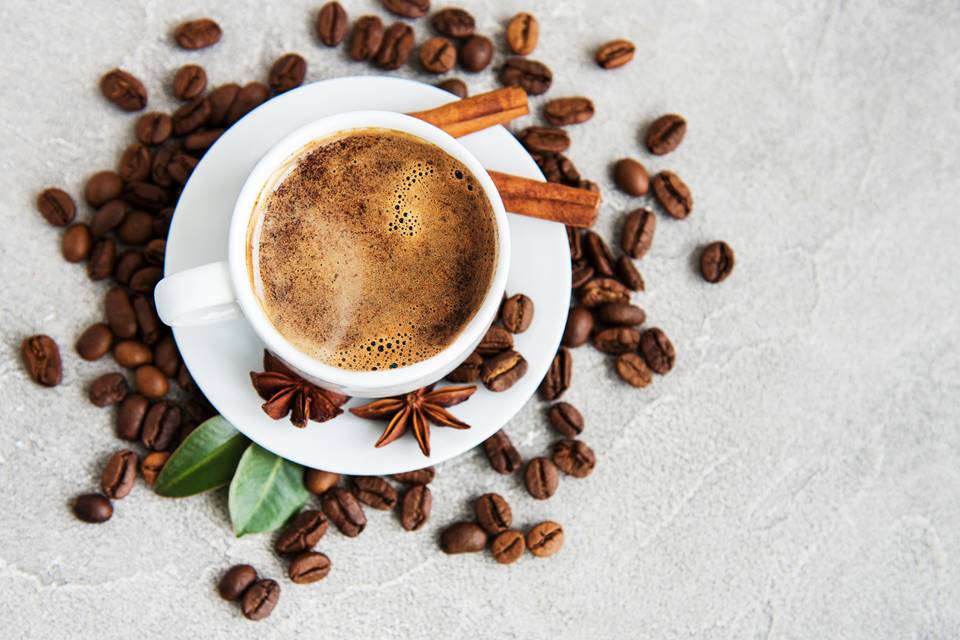 Na foto, uma xícara de café e grãos vistos de cima