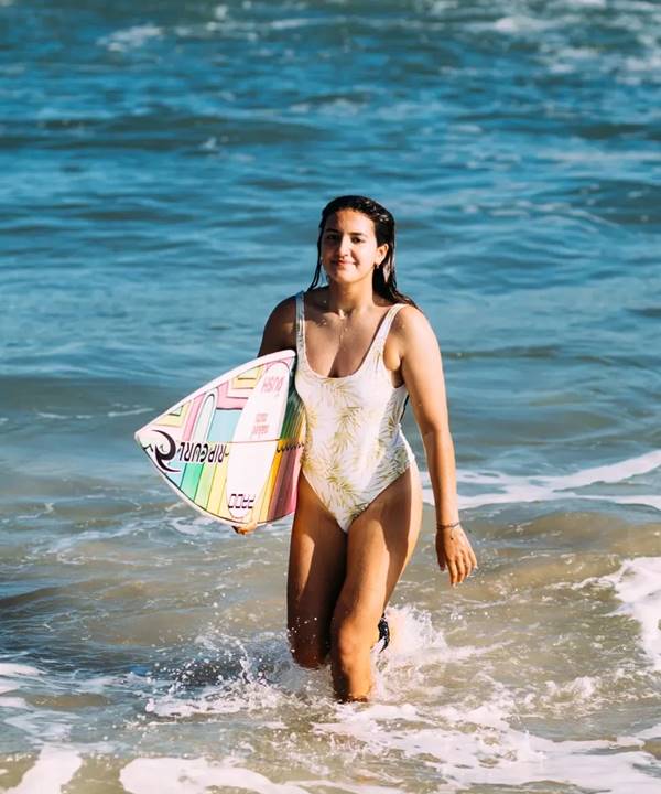 Sophia Medina com biquini branco ao lado de uma prancha de surfe saindo do mar - Metrópoles 