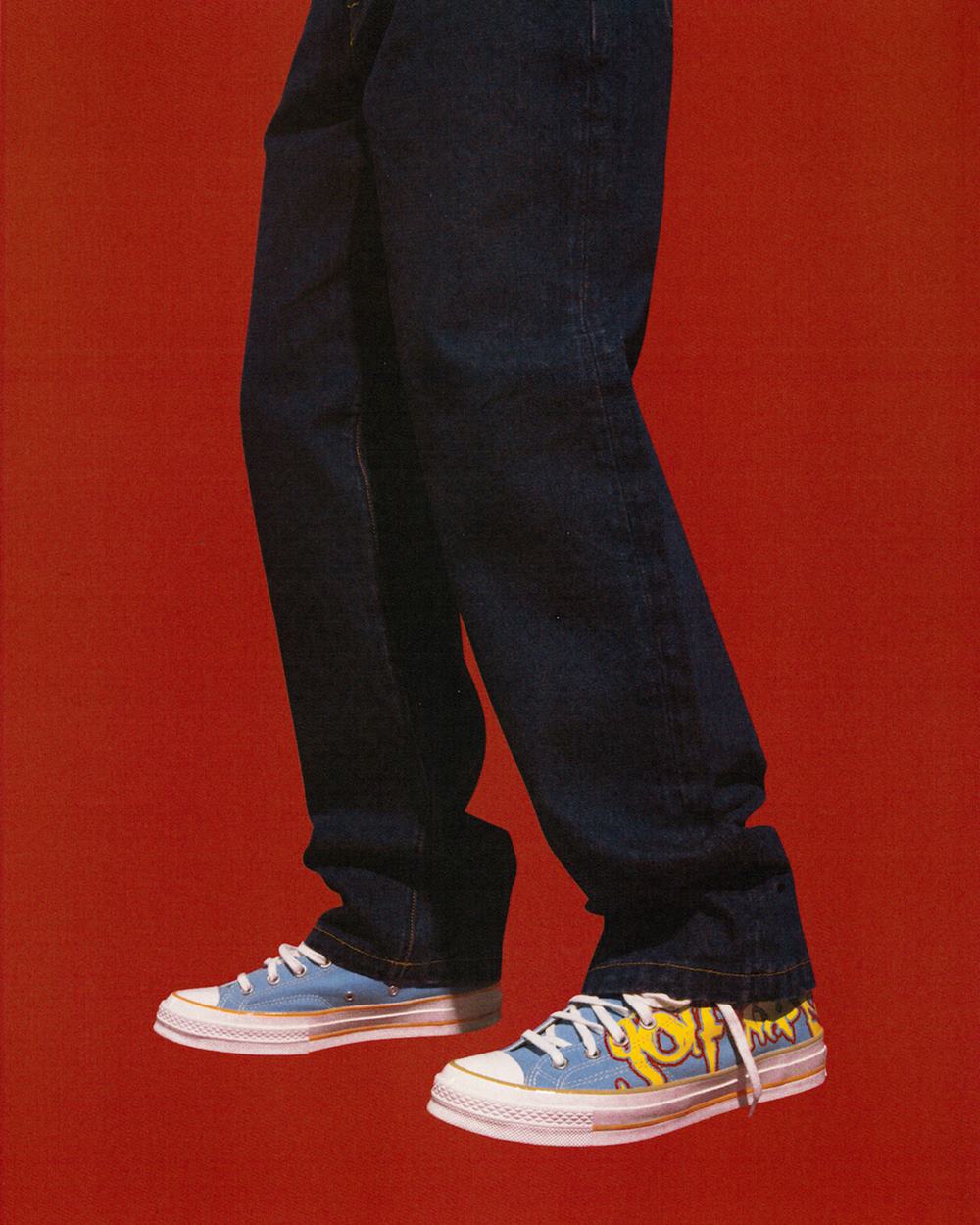 Foto de campanha da marca Converse em que aparece um tênis Chuck Taylor azul e uma calça jeans preta. - Metrópoles