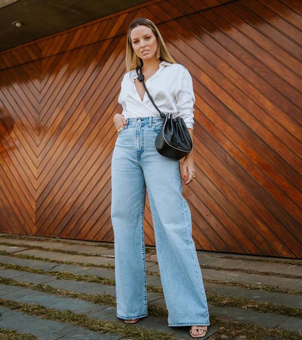 mulher branca e loira usa camisa branca e calça jeans de lavagem clara - Metrópoles 