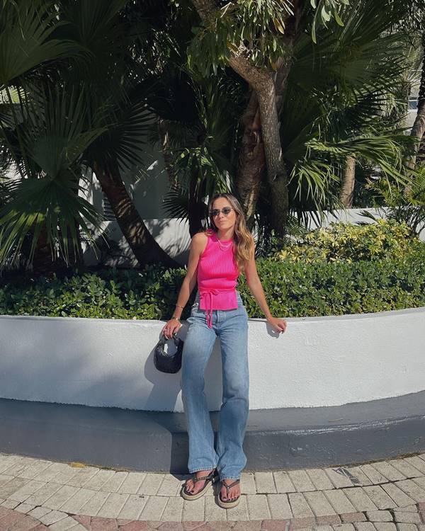 mulher branca e magra usa top rosa e calça jeans - Metrópoles 