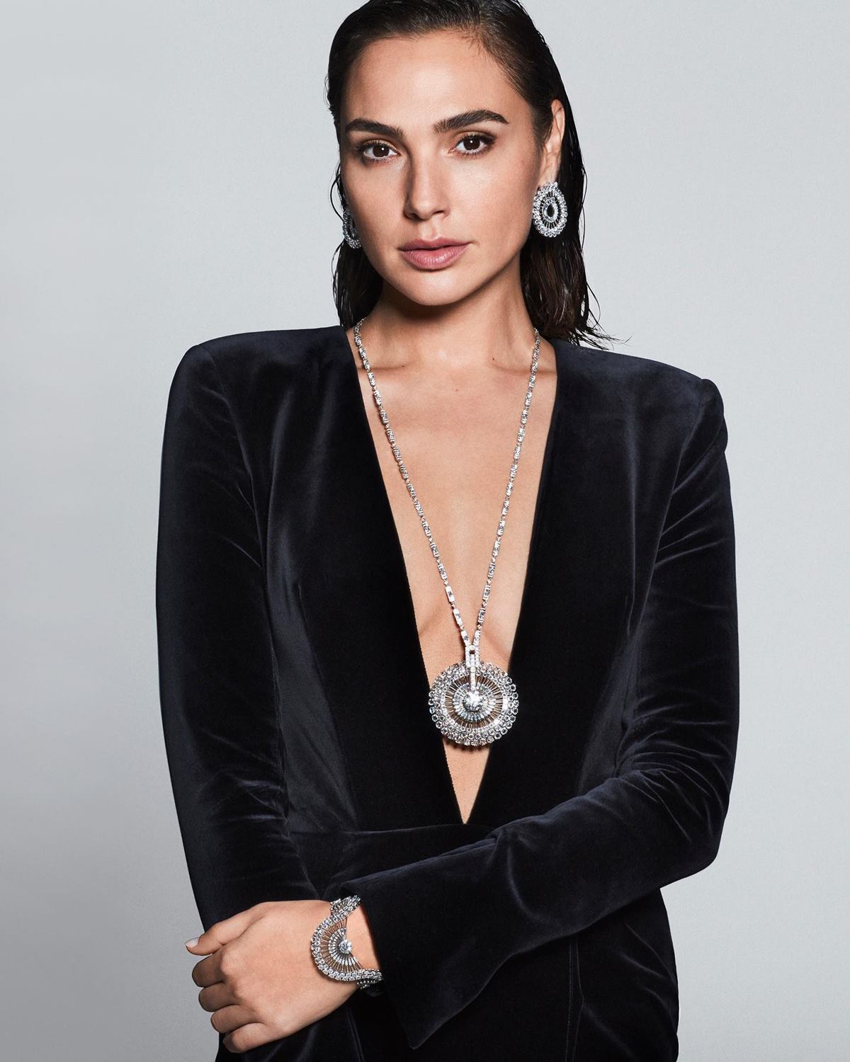 A atriz Gal Gadot em foto de campanha da marca Tiffany & Co. Ela é uma mulher branca e jovem, de cabelo preto liso; e usa um vestido preto de camurça, um colar e um par de brincos da joalheria. - Metrópoles