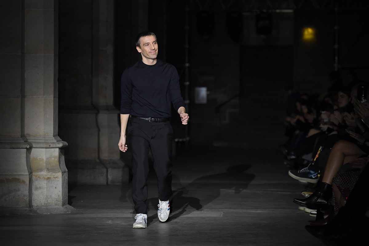 O estilista francês Julien Dossena, um homem branco e jovem, de cabelo castanho curto, no desfile da marca Paco Rabanne. Usa uma blusa e uma calça, ambas pretas, e um tênis branco. - Metrópoles