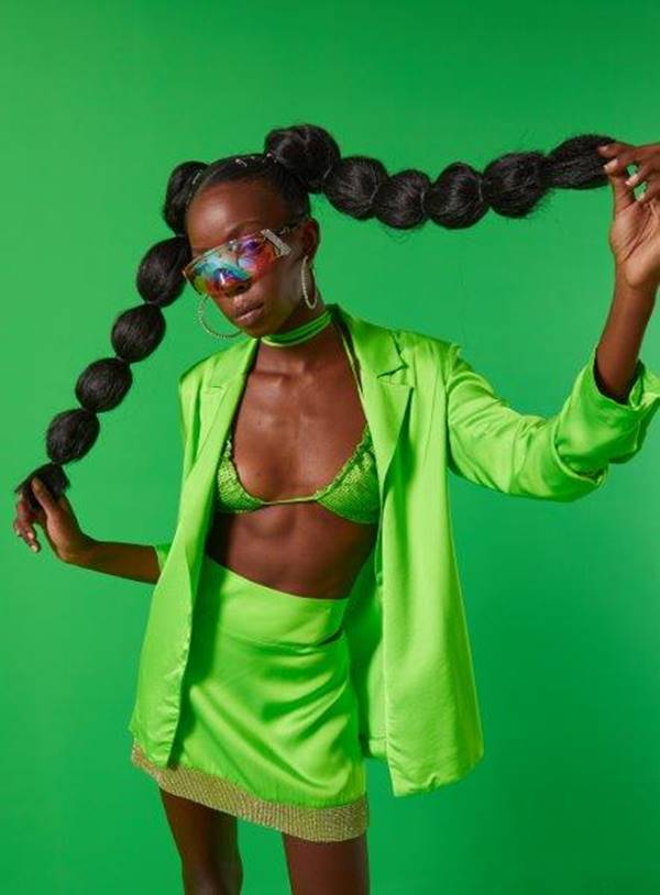 Com look verde, modelo negra segura tranças no cabelo - Metrópoles