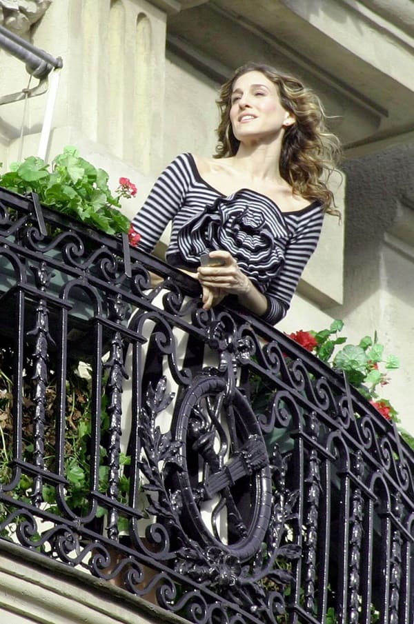 atriz Sarah Jessica Parker em varanda do hotel Plaze, em Paris, usa blusa listrada com uma grande flor no centro - Metrópoles 