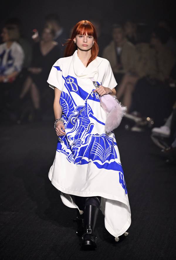 Na passarela, modelo usa vestido branco fluido com estampa azul da logomarca da Burberry - Metrópoles