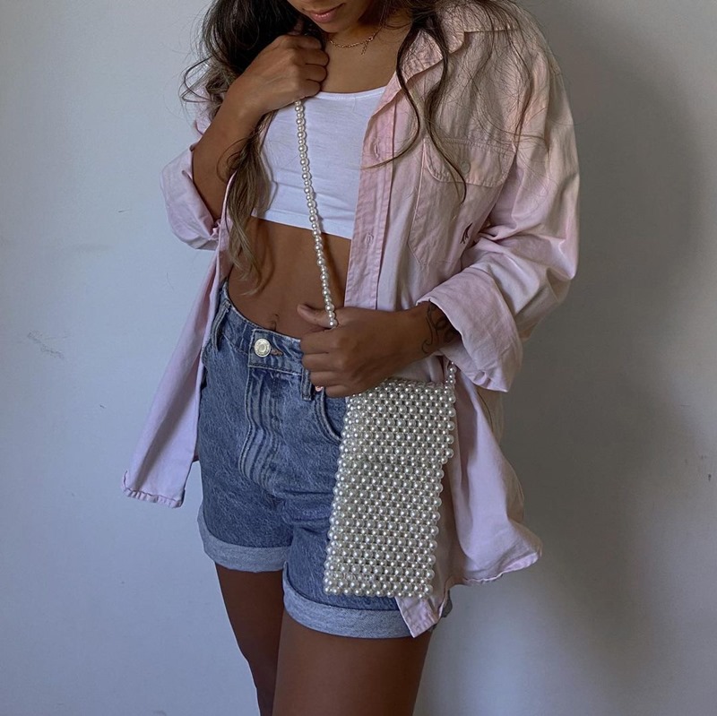 Modelo usa bolsa de pérolas e camisa rosa claro, short jeans e top branco - Metrópoles 