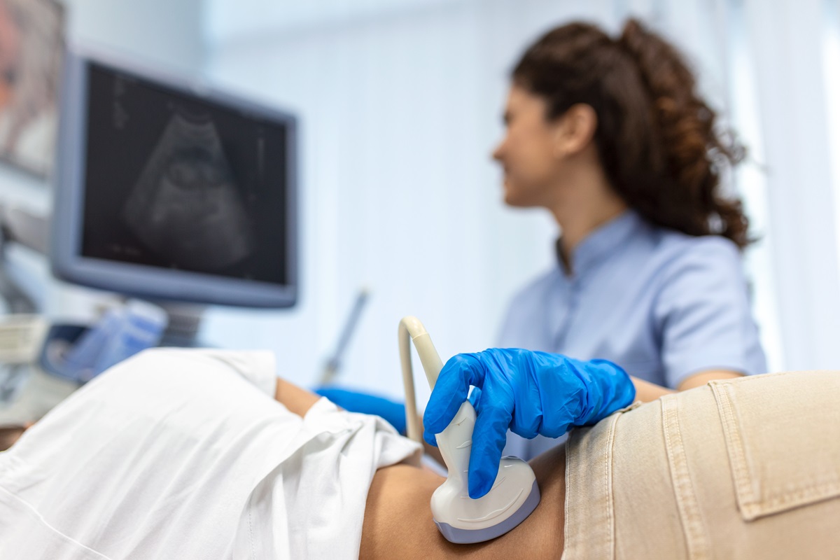 Foto colorida de médica passando equipamento de ultrassom em paciente deitado de lado - Metrópoles