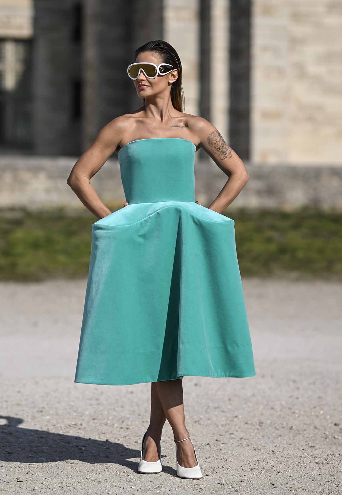 A influenciadora Andressa Suita, esposa do cantor Gusttavo Lima, posa para foto em desfile na Semana de Moda de Paris. Ela é uma mulher branca e jovem, de cabelo liso loiro, e usa um vestido verde claro de camurça e óculos de sol com lente espelhada. As pelas são da marca Loewe. - Metrópoles