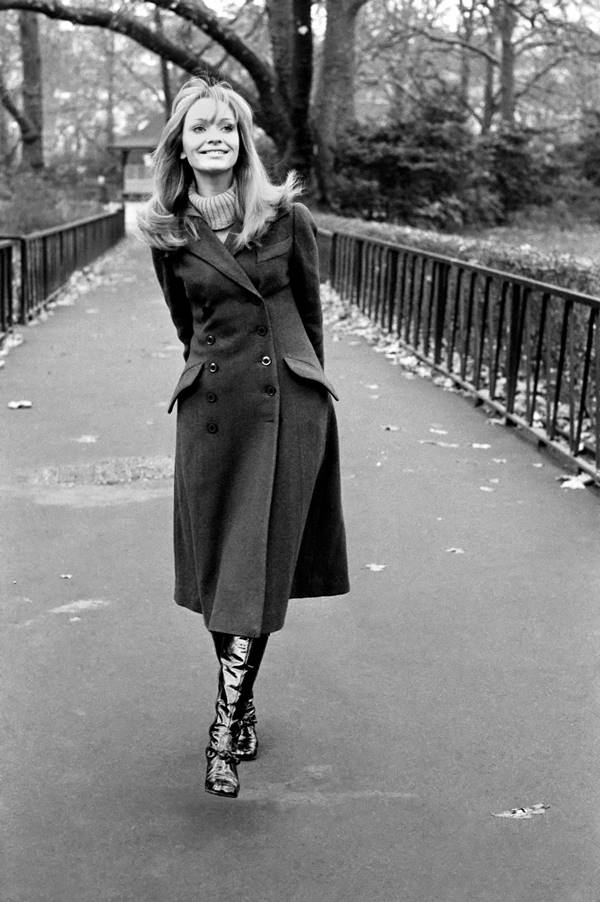 Mulher branca andando em uma ponte. Ela está sorrindo e com as mãos para trás do corpo - Metrópoles