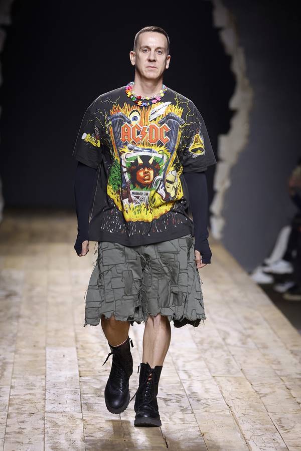 Jeremy Scott na passarela da Moschino. Ele usa bermuda jeans, coturno preto e camiseta da banda ACDC - Metrópoles