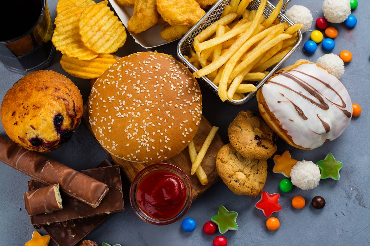 Foto colorida de hambúrguer, batata-frita, donuts, confetes e bombons - Metrópoles